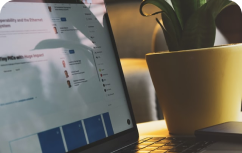 Computador de costado al lado de un macetero con una planta