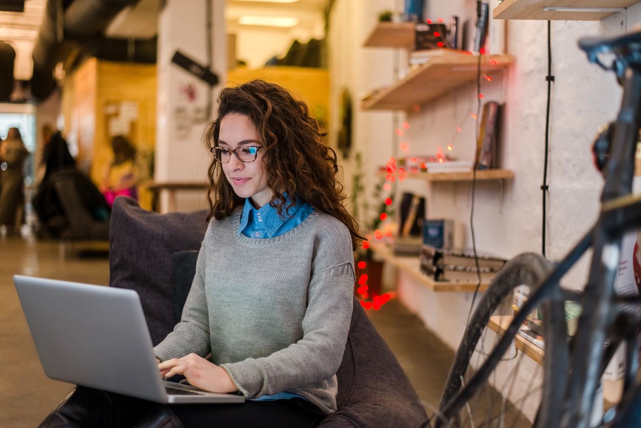 Mujer sentada trabajando con un computador entre las piernas